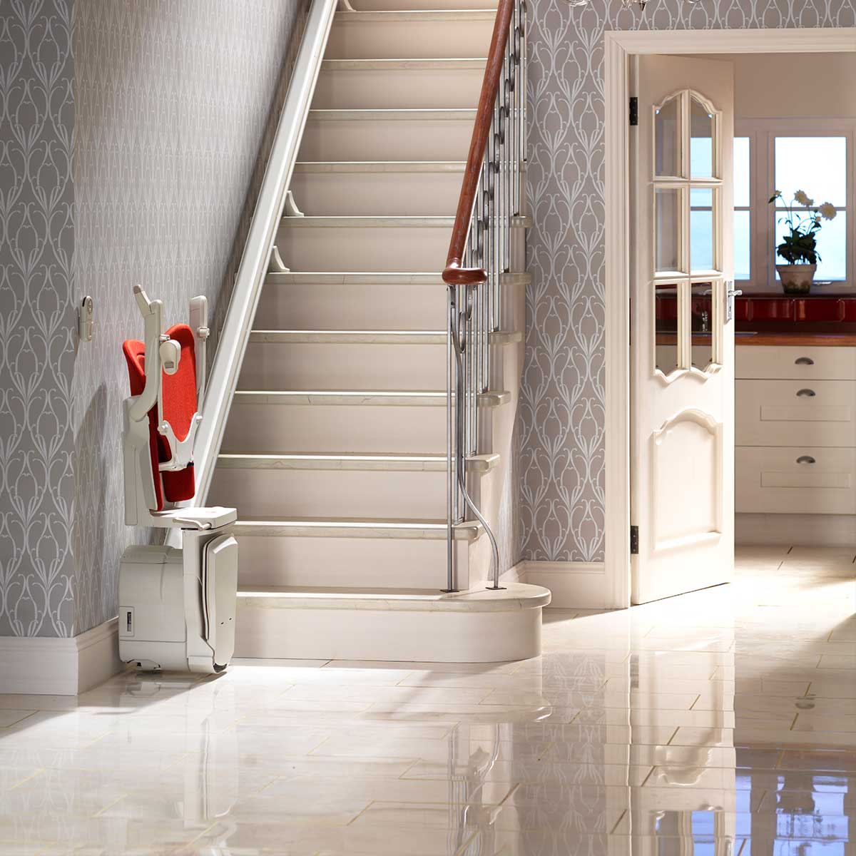 Ein helles elegantes Wohninterieur mit einer Treppe mit eingebautem Treppenlift poliertem weißen Fliesenboden und einer teilweise sichtbaren offenen Tür die in einen anderen Raum führt